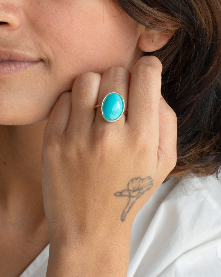 Woman wearing a turquoise ring on her finger against a neutral background